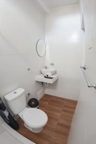a white bathroom with a toilet and a sink at Mystic Paracas Hotel & Glampings in Paracas