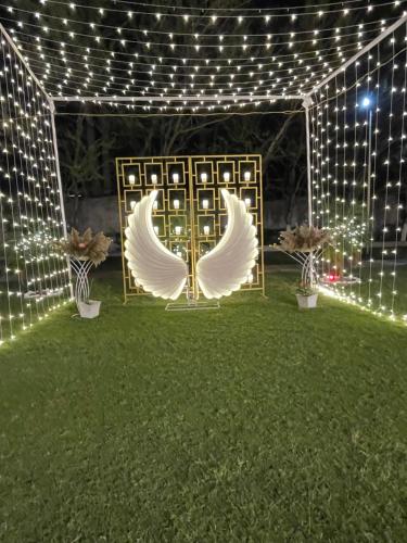 a pergola with white angel wings and lights at Shree farms in Delhi
