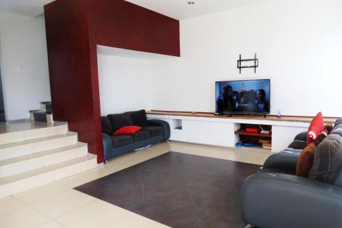 a living room with two couches and a flat screen tv at Casa de descanso en Burgos Temixco Morelos in Temixco