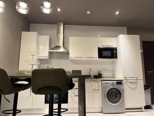 a kitchen with white cabinets and a table with a washing machine at Signature View Apartment in Accra