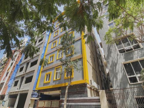 a yellow and gray building with palm trees in front at Super Hotel O New Cyber Grand Madhapur in Hyderabad