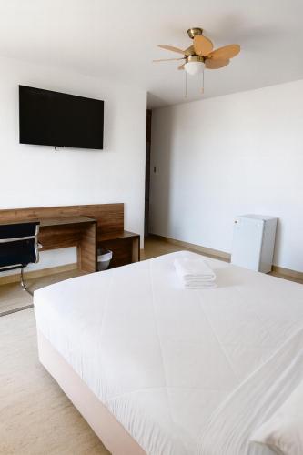 a bedroom with a white bed and a flat screen tv at Mystic Paracas Hotel & Glampings in Paracas