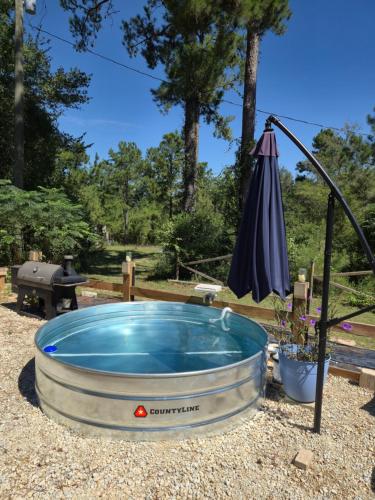a hot tub with an umbrella in a yard at Cabin close to FL Caverns! Pool, WI-FI, & Firepit in Marianna