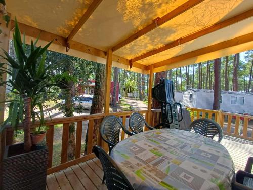 a wooden deck with a table and chairs on a porch at MOBIL HOME à SEIGNOSSE dans les Landes près de la mer in Seignosse
