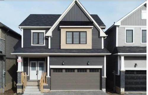 a black house with a garage at Two Adjacent Modern Homes in West Niagara Sleep 16 in Thorold
