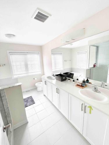 a white bathroom with a sink and a toilet at Two Adjacent Modern Homes in West Niagara Sleep 16 in Thorold