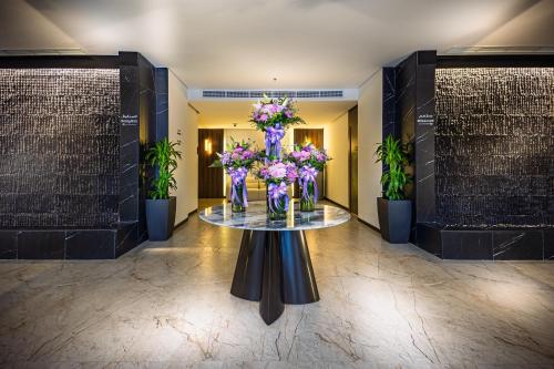 a lobby with a table with a vase of flowers at Tuvana Hotel in Jeddah