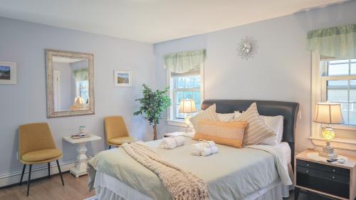 a bedroom with a bed with two chairs and a mirror at Diana House in Charlottetown
