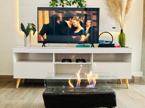 a living room with a fireplace and a tv at Uai House com jacuzzi, teto rooftop retrátil e colchão massageador in Poços de Caldas
