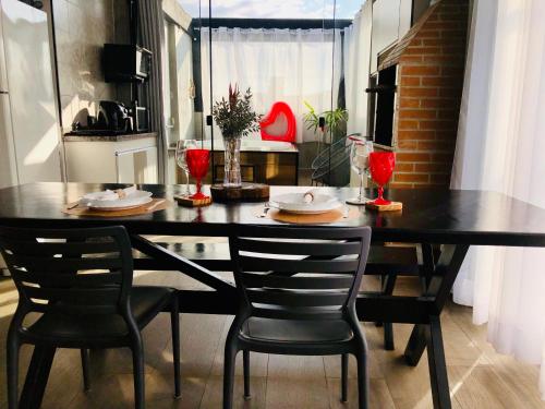 a dining room table with two chairs and a black table at Uai House com jacuzzi, teto rooftop retrátil e colchão massageador in Poços de Caldas