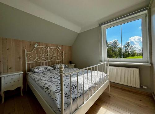 a bedroom with a bed and a large window at Ergli Holiday Apartments in Ērgļi