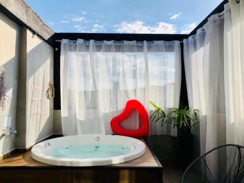 a red chair sitting in a tub in front of a window at Uai House com jacuzzi, teto rooftop retrátil e colchão massageador in Poços de Caldas