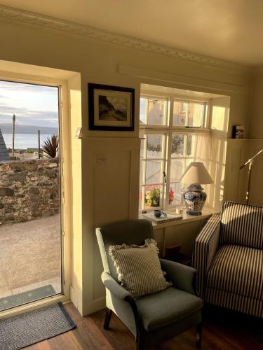 ein Wohnzimmer mit einem Stuhl und einem Fenster in der Unterkunft Emma's Cottage in Glenarm