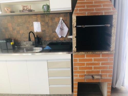 a kitchen with a brick oven next to a brick wall at Uai House com jacuzzi, teto rooftop retrátil e colchão massageador in Poços de Caldas