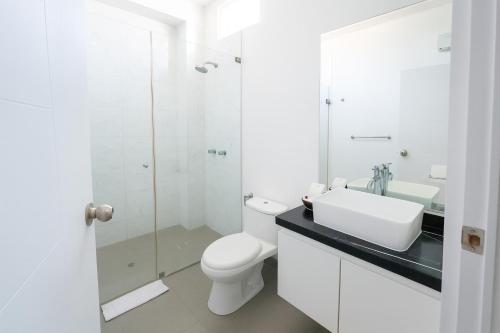a white bathroom with a toilet and a sink at Mystic Paracas Hotel & Glampings in Paracas