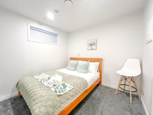 a bedroom with a bed and a white chair at SUPER Location - Modern 2Br Apt-Pool & Gym in Auckland