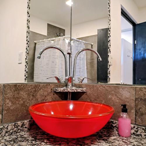 a red sink in a bathroom with a faucet at Nina Hostel in San Carlos de Bariloche