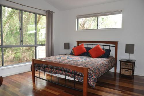 a bedroom with a bed with red pillows at Csalt - Rainbow Shores in Rainbow Beach