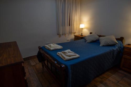 ein Schlafzimmer mit einem blauen Bett mit Handtüchern darauf in der Unterkunft La Chuklla, alojamiento cerca al lago in Almafuerte