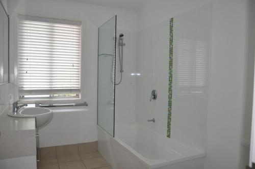 a white bathroom with a shower and a sink at Csalt - Rainbow Shores in Rainbow Beach
