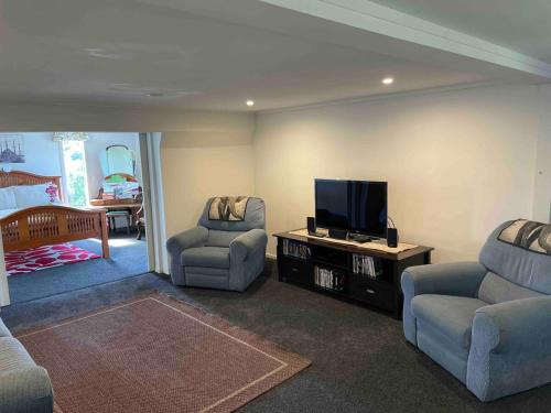 Una sala de estar con dos sillas y un televisor de pantalla plana. en Otumoetai 2 bedroom, en Tauranga