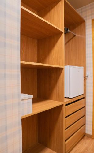 a kitchen with wooden shelves with a microwave in it at Suítes no Chalé - Cabanas in Campos do Jordão