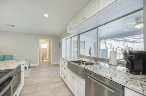 a kitchen with white cabinets and marble counter tops at The Seaside Retreat, FREE heated pool in Apollo Beach