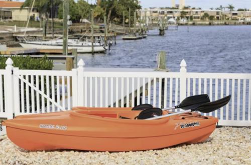 an orange boat sitting on the beach next to a fence at The Seaside Retreat, FREE heated pool in Apollo Beach
