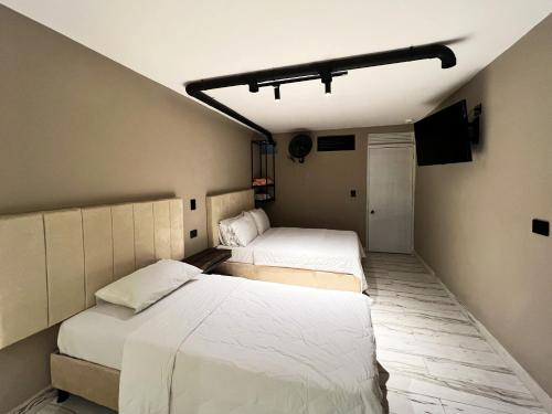 two beds in a small room with at Hotel Natural Medellin in Medellín