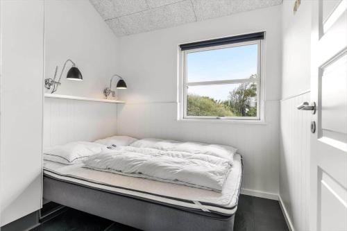 a small bed in a room with a window at HS006-Henne-Musvagevej-18 in Henne Strand