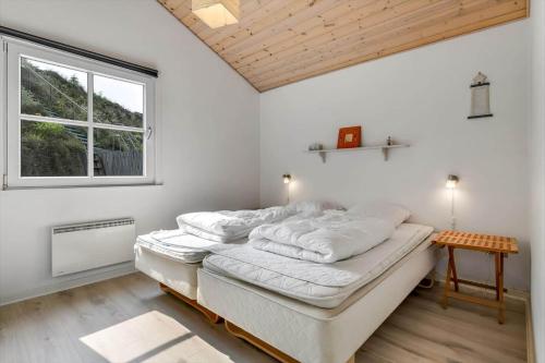 a bedroom with a bed with white sheets and a window at HS008-Henne-Porsevej-10 in Henne Strand