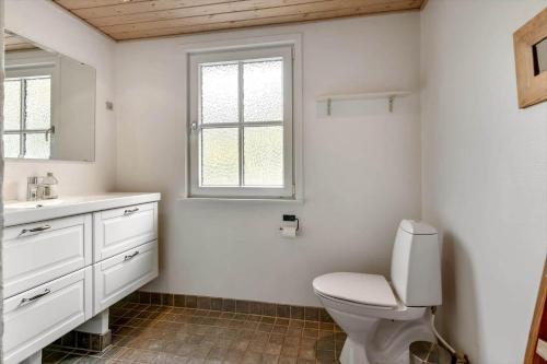 a bathroom with a toilet and a sink and a window at HS008-Henne-Porsevej-10 in Henne Strand