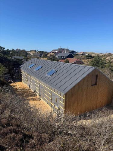 a building with a metal roof on top of a hill at HS001-Henne-Enebaervej-6 in Henne Strand