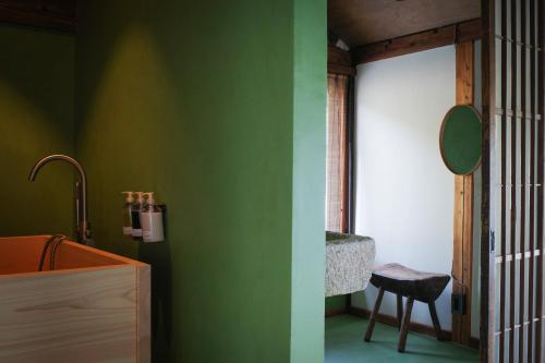 a bathroom with green walls and a sink and a chair at Akitsu Ryokan in Maibara