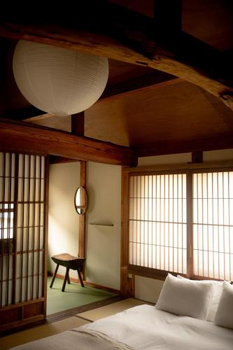 a room with a bed and windows and a table at Akitsu Ryokan in Maibara