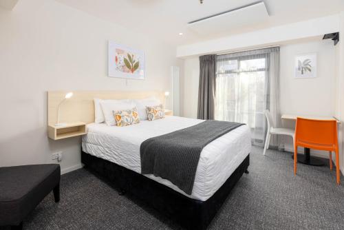 a hotel room with a bed and a desk and a window at Hotel Give in Christchurch