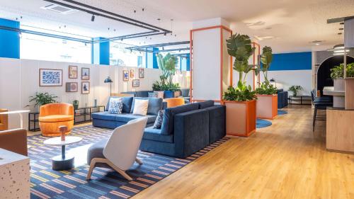 a lobby with a blue couch and chairs and plants at Holiday Inn Express & Suites Lisbon - Príncipe Real by IHG in Lisbon