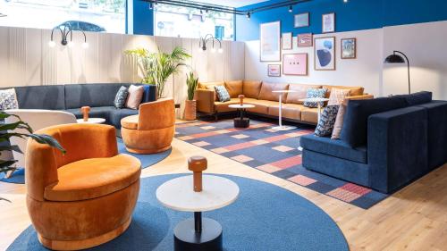 a living room with couches and chairs on a rug at Holiday Inn Express & Suites Lisbon - Príncipe Real by IHG in Lisbon
