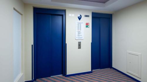 a hallway with two blue doors in a building at Holiday Inn Express & Suites Lisbon - Príncipe Real by IHG in Lisbon