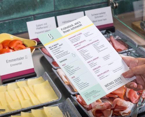 a person holding a menu in front of meats and cheese at Garner Hotel Elmshorn by IHG in Elmshorn