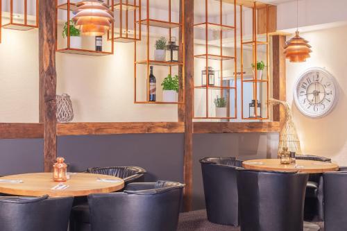 a restaurant with two tables and chairs and a clock at Garner Hotel Elmshorn by IHG in Elmshorn