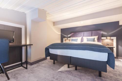 a bedroom with a king sized bed and a tv at Garner Hotel Elmshorn by IHG in Elmshorn