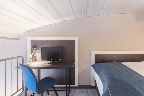 a bedroom with a desk with a tv and a bed at Garner Hotel Elmshorn by IHG in Elmshorn