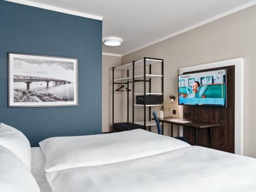 a hotel room with a bed and a flat screen tv at Garner Hotel Elmshorn by IHG in Elmshorn