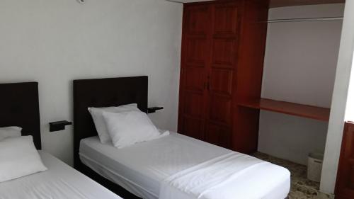 a bedroom with two beds with white sheets and a door at Arena Dorada in Ríohacha