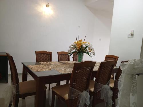 a dining room table with chairs and a vase of flowers at Homestay Alor Setar - VILLA FARAH in Alor Setar