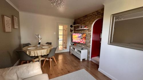 a living room with a table with chairs and a tv at Cozy Apartment in London