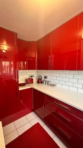 a red kitchen with white counters and red cabinets at Cozy Apartment in London