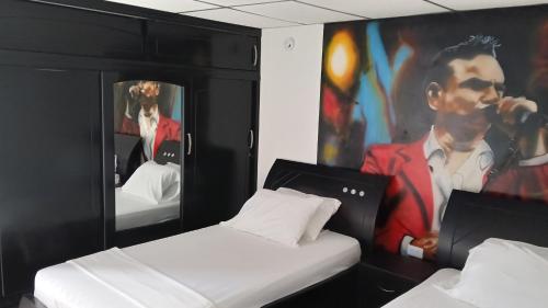 a room with two beds and a painting of a man at Arena Dorada in Ríohacha