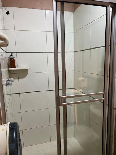 a glass shower door in a white tiled bathroom at Hotel Natural Medellin in Medellín